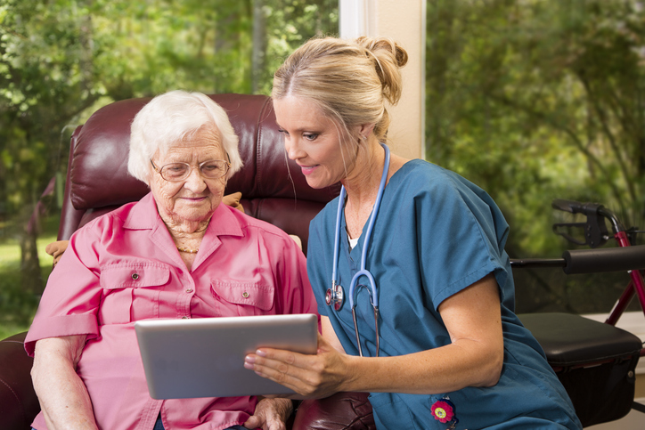 caregiver showing older female adult tablet