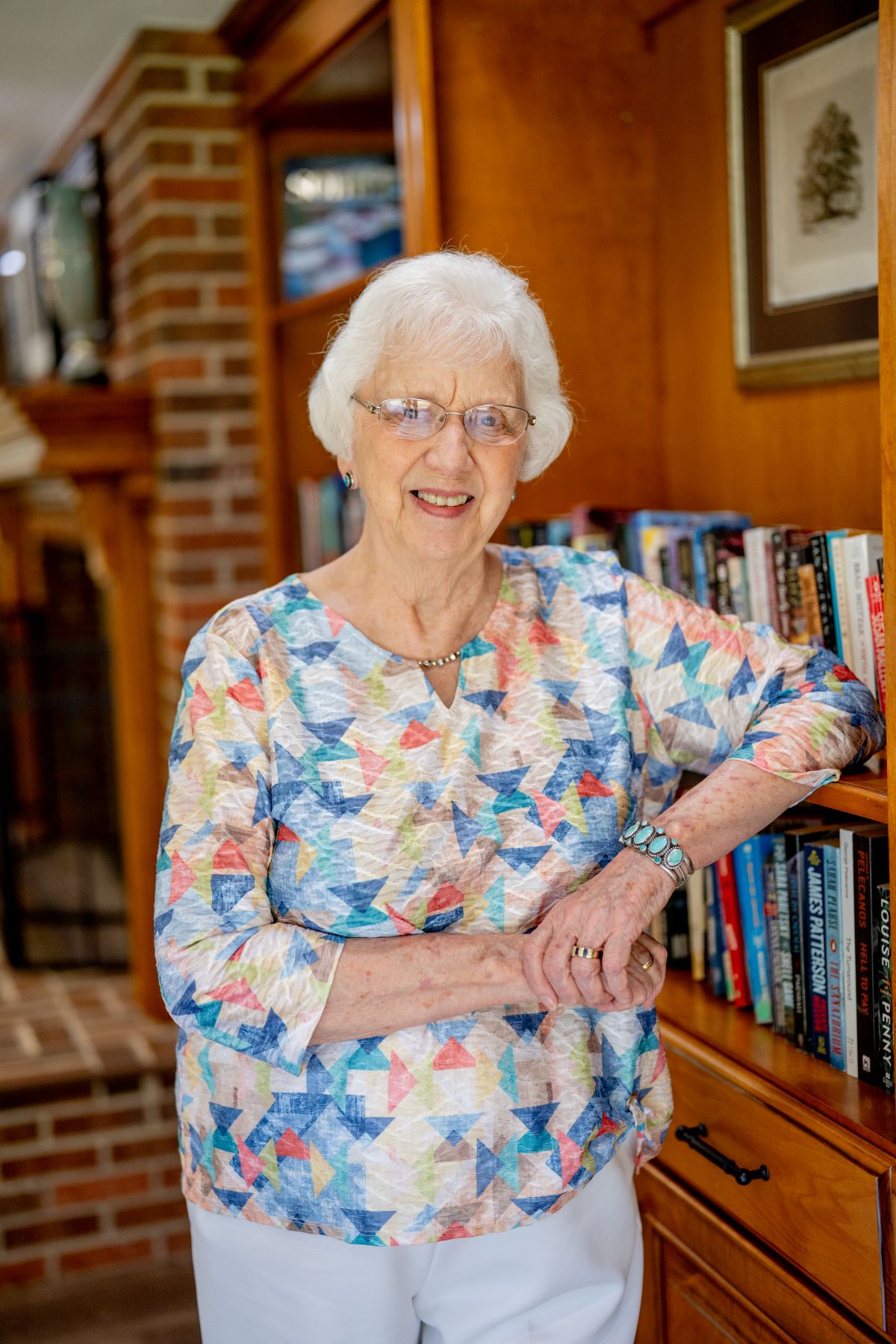 female standing by bookshelf smiling