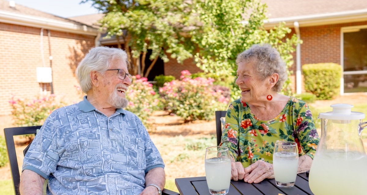 male and female sitting outside at a table with beverages and lite snacks
