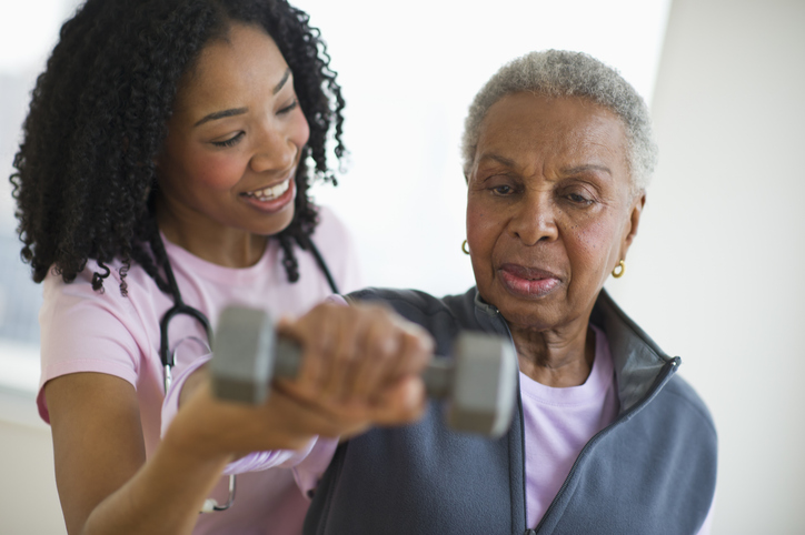 caregiver assisting older female with arm weight
