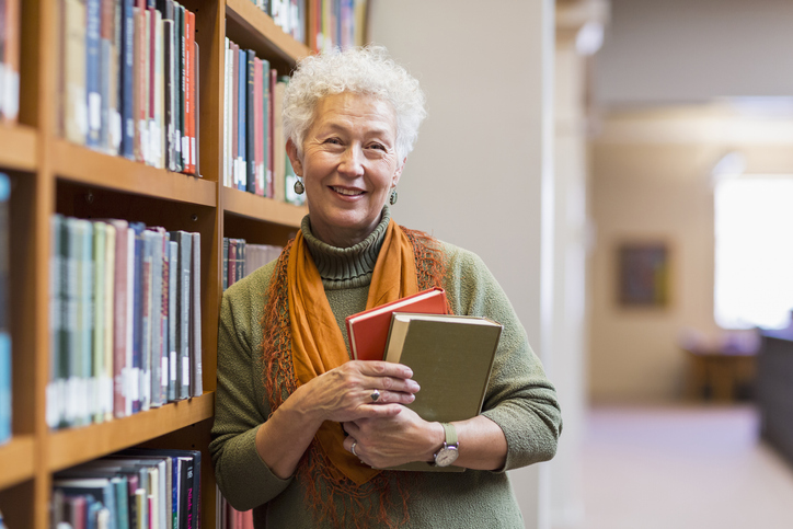 women holding books in front of book shelf
