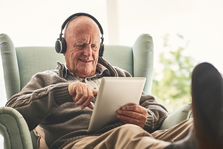 male in chair looking at tablet and listening to music